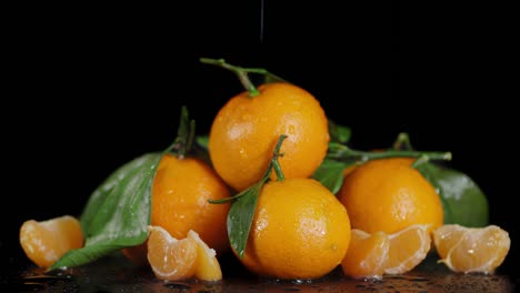 on whole and slices ripe tangerines falling water drops.