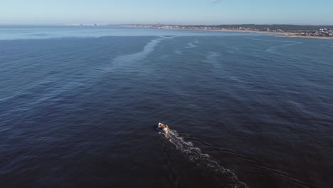 stunning aerial 4k cinematic high angle drone footage of fishing boat navigating in blue ocean water of uruguay