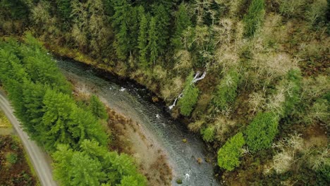 picturesque cascading waterfall joins larger stream, descending circling aerial shot