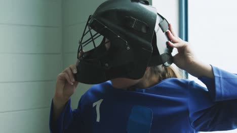 female player putting on her helmet in dressing room