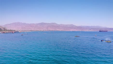 eilat beach scene with boats and mountains