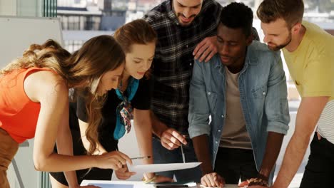 Group-of-colleagues-discussing-over-document