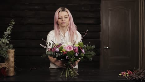 A-girl-puts-on-a-table-a-decorated-bouquet-of-flowers.-Surprised-and-laughs.-Bouquet-in-the-foreground.-The-dark-interior.-Slow-motion