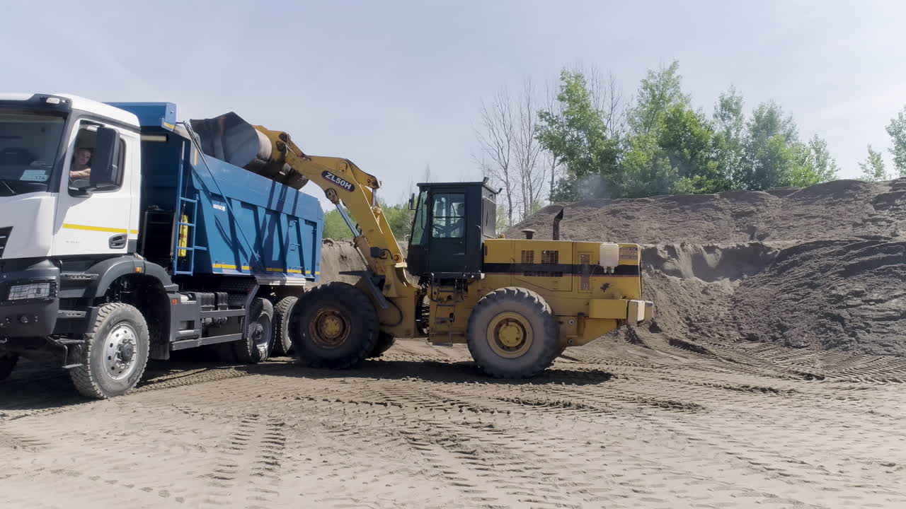 Excavator loading dump truck with sand/gravel/dirt