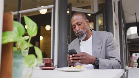 hombre afroamericano usando su teléfono en un café