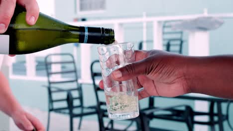 pouring wine into tall cup held by hand, chairs out of focus