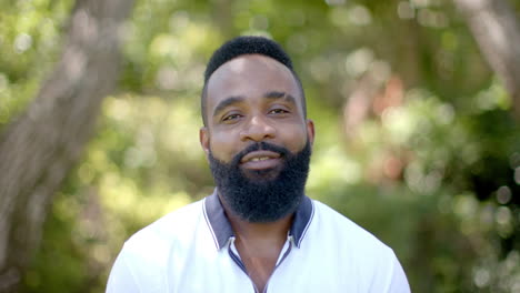 african american man with beard smiling outdoors, in backyard garden