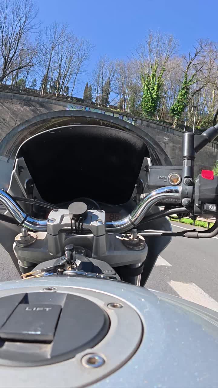 Vista in prima persona di una moto che attraversa un tunnel illuminato.