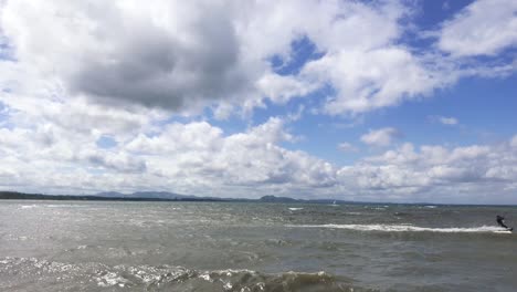 a kite surfer moving past at speed, with another surfer in the background, on a windy summer day | portobello beach, edinburgh | shot in hd at cinematic 24 fps