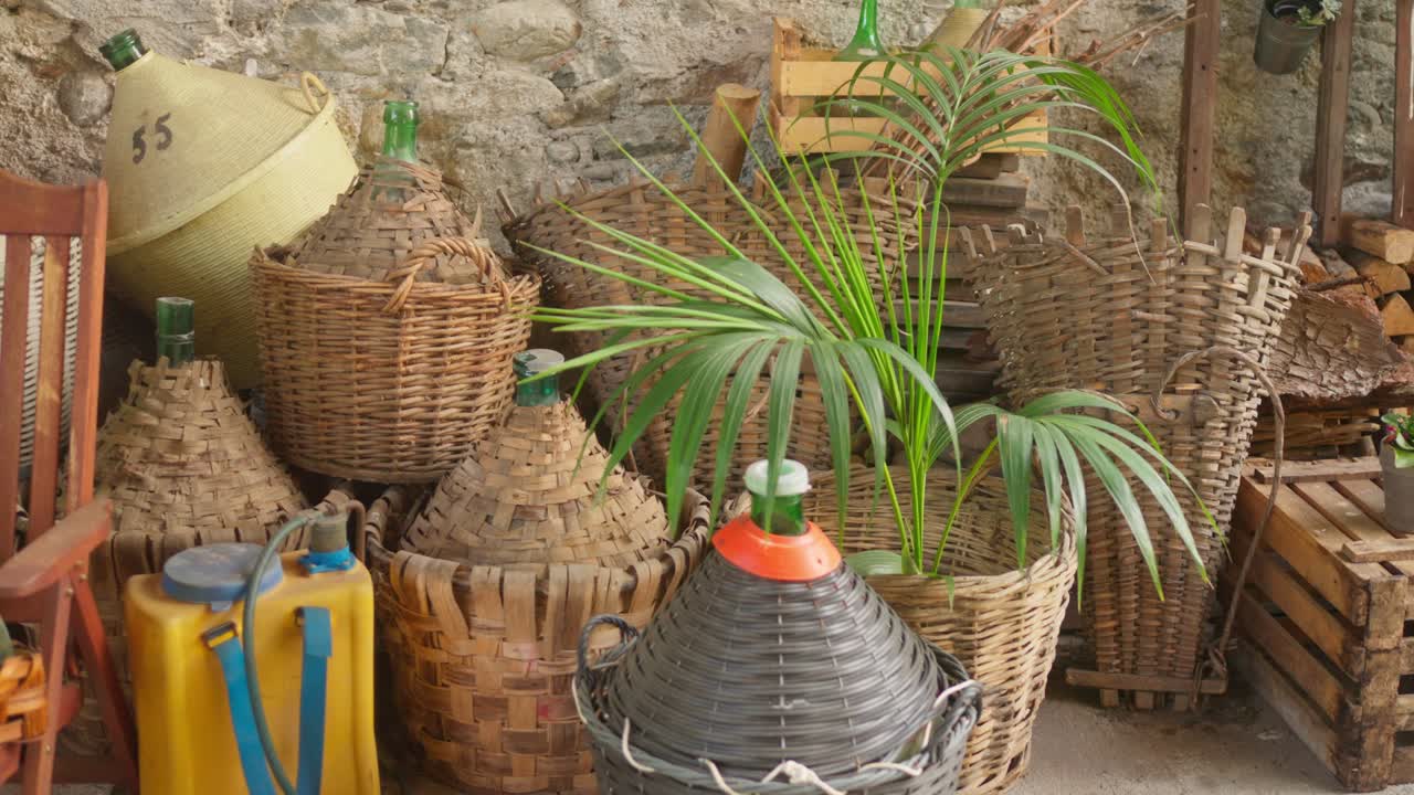 Collezione di strumenti tradizionali per la vinificazione, inclusi cesti di vimini, brocche di vetro e attrezzature rustiche