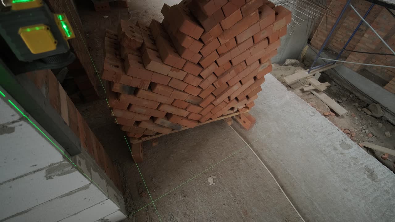 건설자는 녹색 레이저 레벨을 사용하여 수리 라인을 측정합니다.