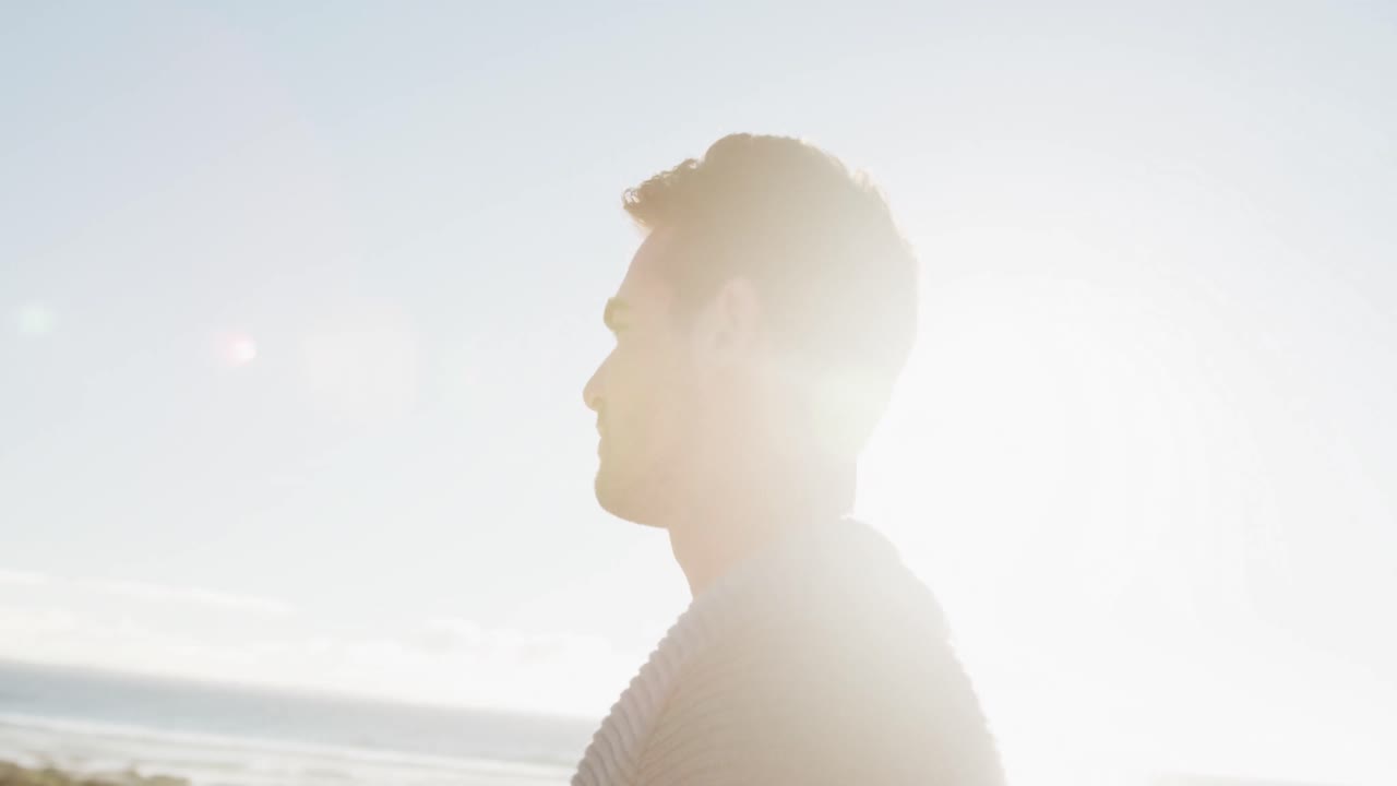 행복한 백인 남자가 바 ⁇ 가에 서서 웃고 있습니다.