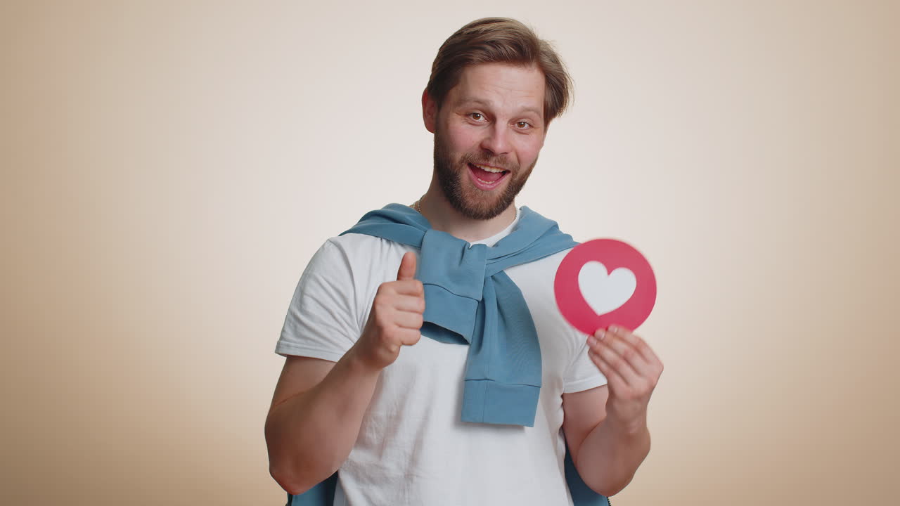 Smiling man showing heart banner demonstrates love sign expresses good feelings positive reply like