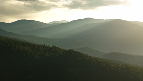 stunning light rays cast over mountains above peaks in idaho springs, colorado, featuring the sun setting behind the mountains with soft lighting over the landscape