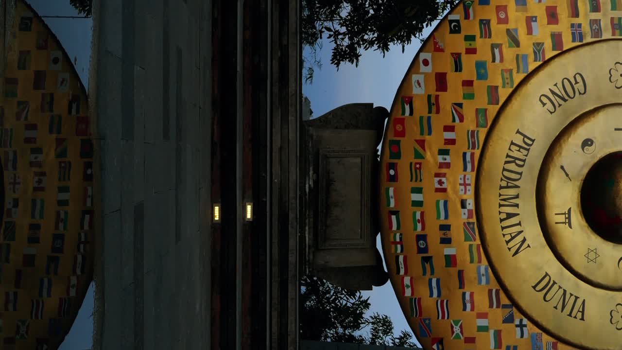 Plano vertical a cámara lenta con movimiento de inclinación del Gong de la Paz Mundial en Bali, simbolizando la unidad y la paz entre diferentes religiones, con una majestuosa escultura de elefante de piedra a su lado