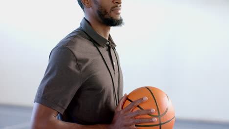 entrenador afroamericano tiene una pelota de baloncesto