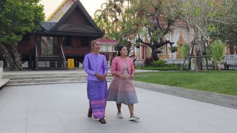 two women in traditional thai clothing at a temple