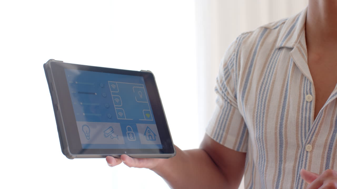 Person using tablet to control smart home security system indoors