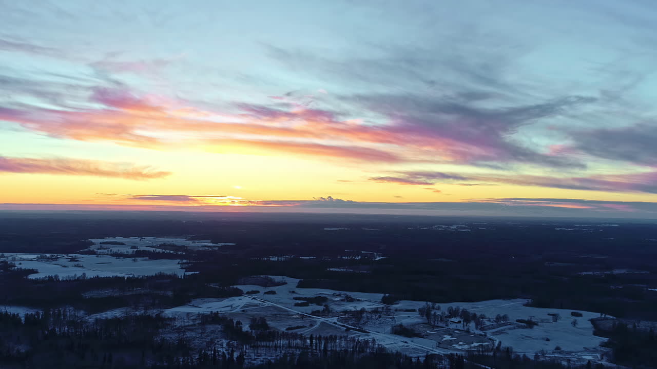 시간경과에서 일출 동안 침엽수 나무가 있는 눈 덮인 풍경 위로 공중 드론이 뒤로 이동하는 샷