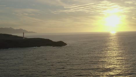 drone disparó panorama de un faro a la hora dorada con el océano y el sol en el fondo