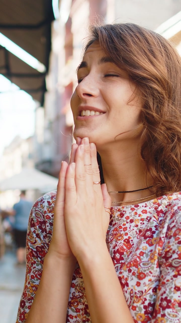 Retrato de una mujer rezando al aire libre con los ojos cerrados, pidiéndole a Dios una bendición, ayuda y perdón.