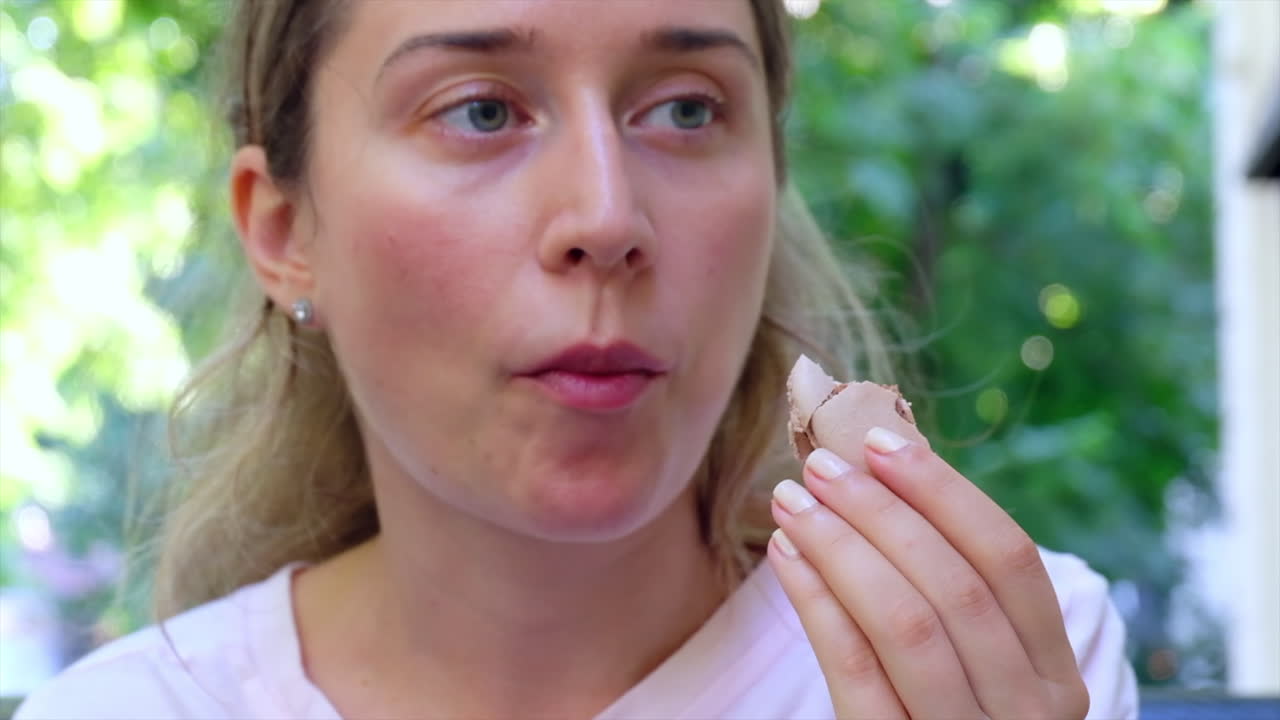 Close up of a woman eating chocolate macarons at a terrace
