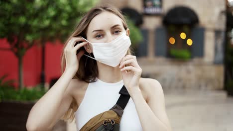 mujer poniendo una máscara médica para la protección contra el coronavirus al aire libre