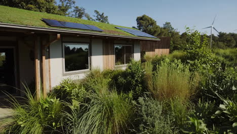 eco-friendly home with green roof, solar panels, and wind turbines in a lush garden setting