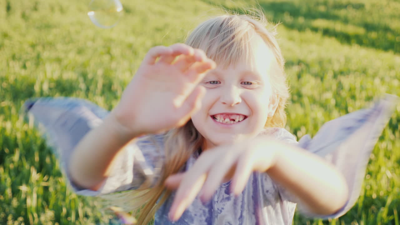 Uma Menina Alegre Pega Bolhas de Sabão, Seus Dentes de Leite Caíram. Vídeo 4K em Câmera Lenta.