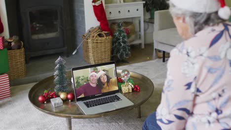 Senior-caucasian-woman-using-laptop-for-christmas-video-call-with-smiling-couple-on-screen