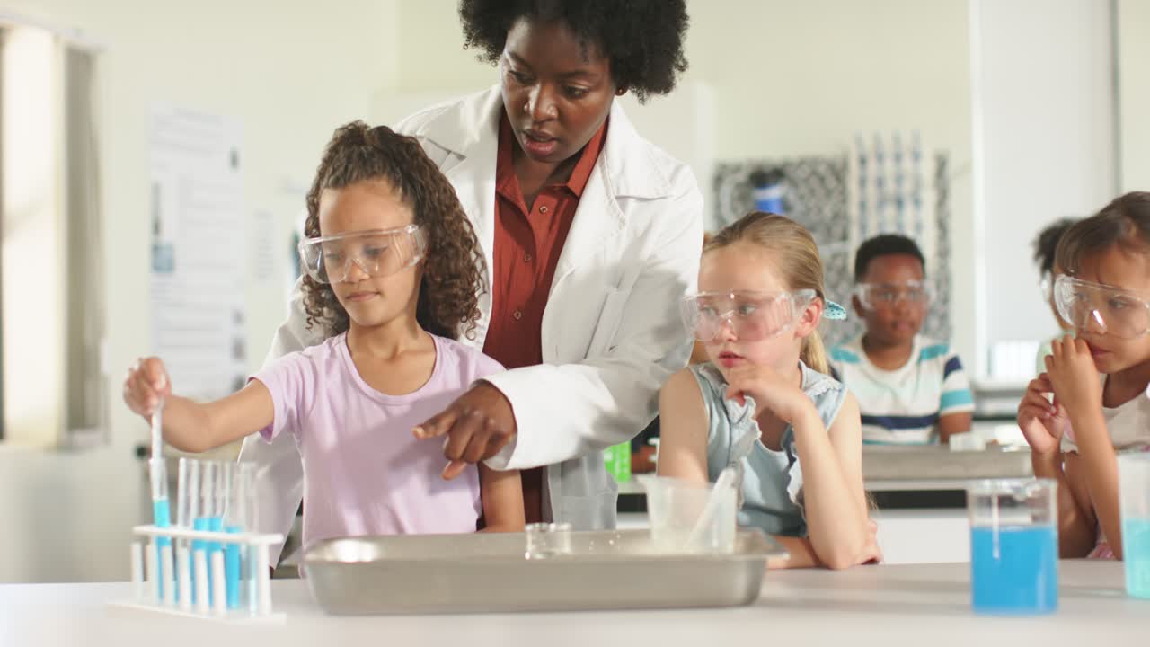 African American teacher pointing and teaching child drawing blue liquid with pipette in school lab