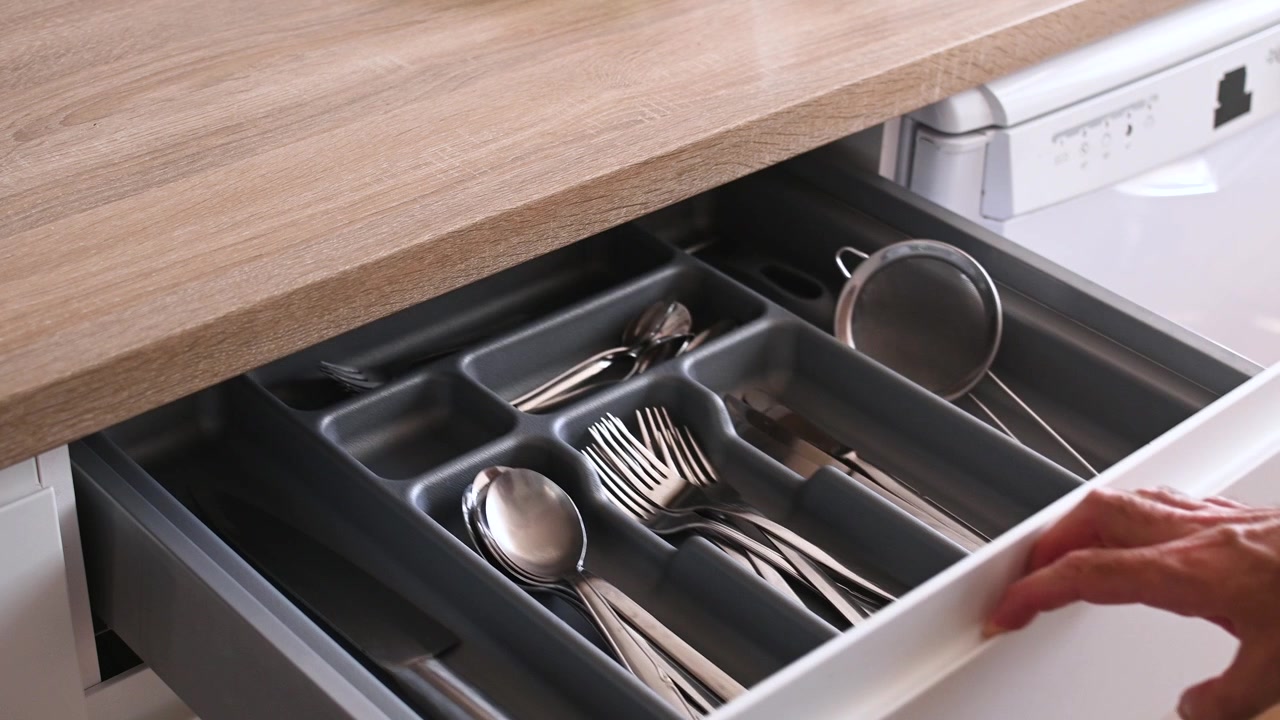 Opening kitchen drawer with organized cutlery and utensils