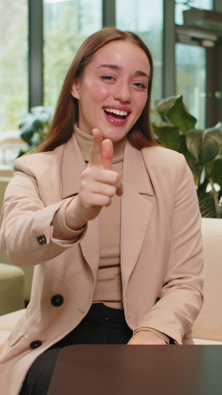 retrato de una joven mujer de negocios caucásica apuntando a la cámara seleccionando alquiler sentada en el vestíbulo de la oficina