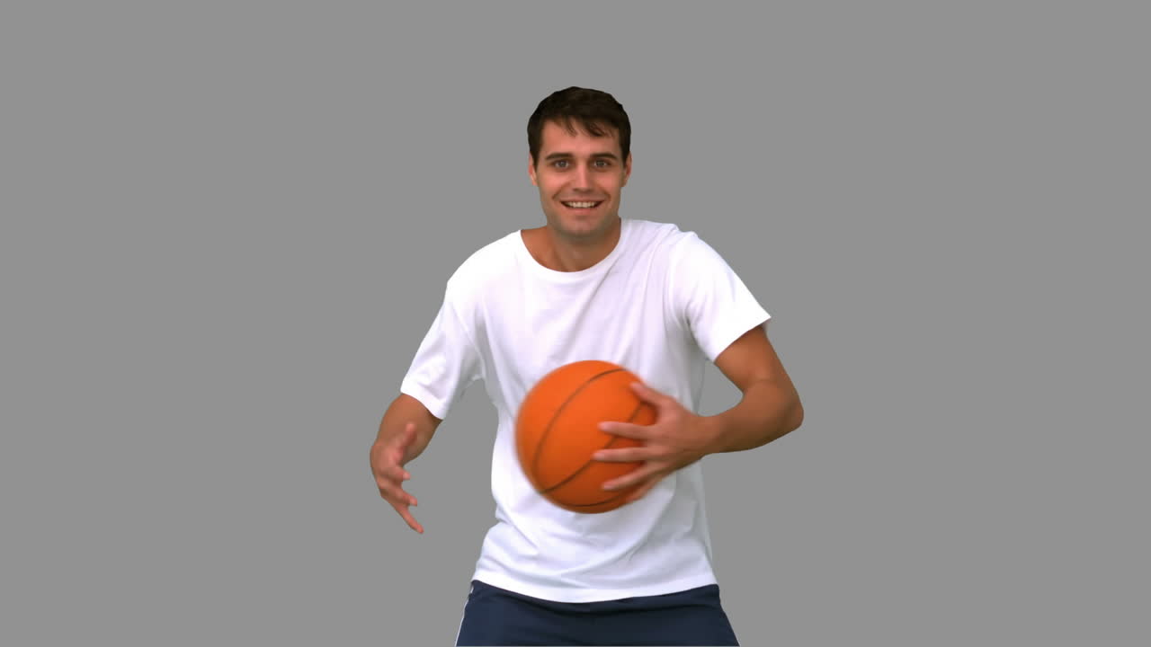 hombre jugando y driblando con una pelota de baloncesto en la pantalla gris