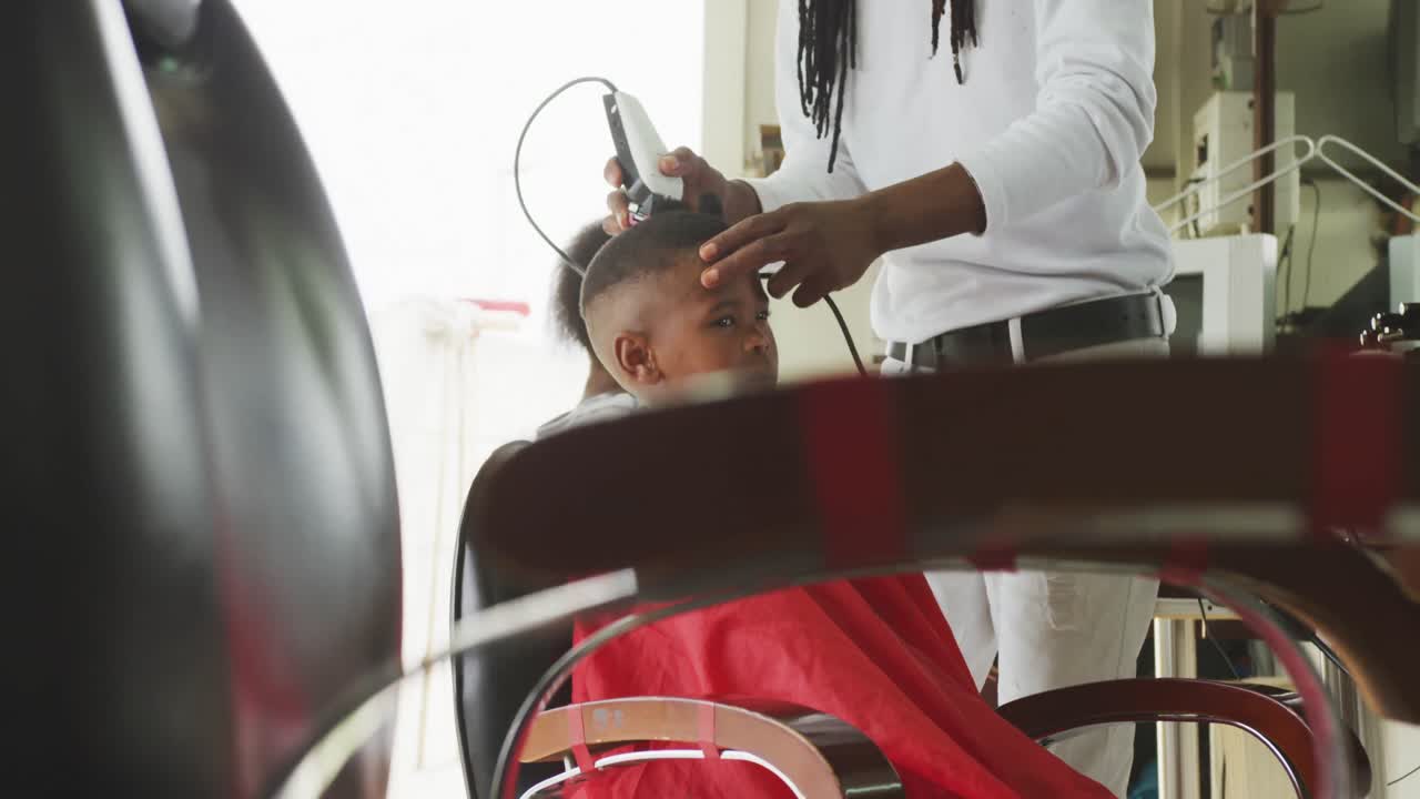 vista lejana de un hombre africano cortando el cabello de un niño africano