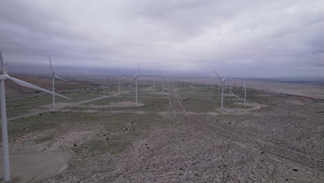 Aerial-footage-of-a-wind-farm-in-the-Palm-Springs-desert-on-a-cloudy-day,-slow-dolly-shot