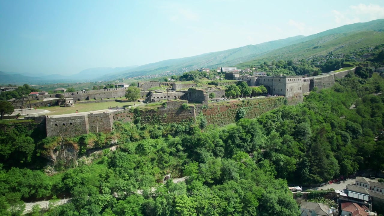 Dağlık bir manzara önünde Gjirokastër Kalesi'nin ters hava çekimi.