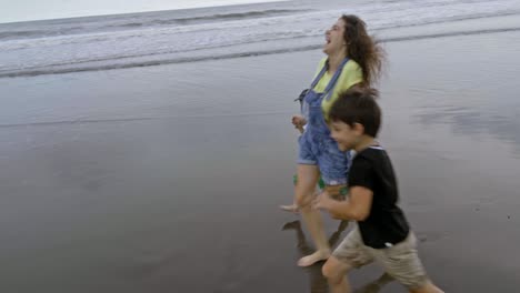 happy family running barefoot on beach