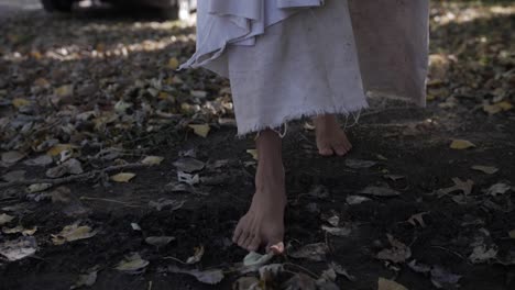 A-dramatic-slow-motion-closeup-of-Jesus'-feet-walking-down-a-sidewalk-while-he-wears-a-white,-tattered-robe