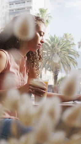 video vertical de una mujer afroamericana bebiendo café en una cafetería