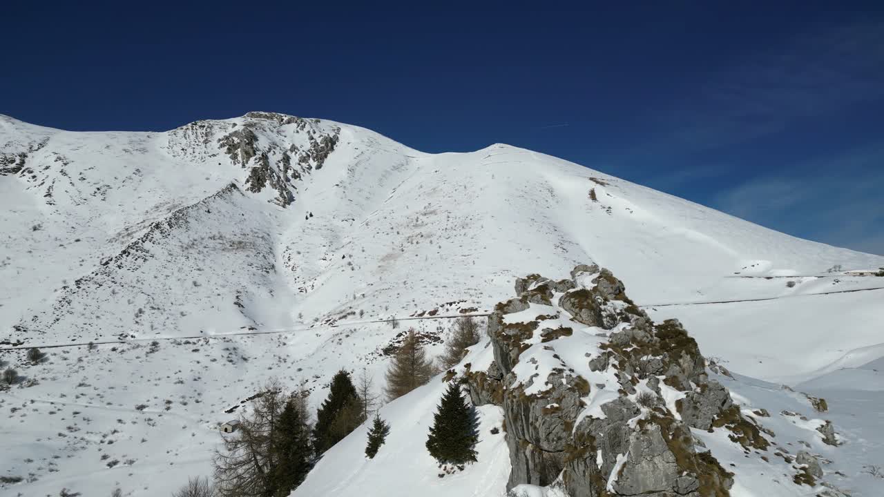 Riprese aeree con drone del Monte Altissimo, Italia: paesaggio alpino innevato con creste rocciose e alberi ghiacciati sotto la chiara luce invernale. Ideale per progetti su natura, montagna e paesaggi
