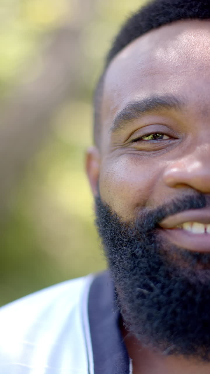 Vertical video: Smiling man with beard enjoying outdoor time in natural sunlight