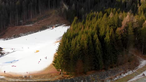 Inclinación-Aérea-Hacia-Abajo-En-Cámara-Lenta-De-Un-Denso-Bosque-Y-Zona-De-Esquí-En-Los-Alpes-Italianos