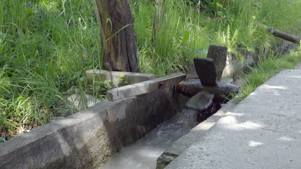 A water wheel in an irrigation canal attached to a wooden alarm mechanism to check the water supply