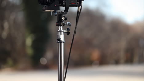 behind-the-scenes of an outdoor video shoot, featuring a camera on a tripod and a crew member adjusting a light modifier