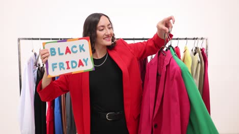 woman holding 'black friday' sign and clothes, excited about sales