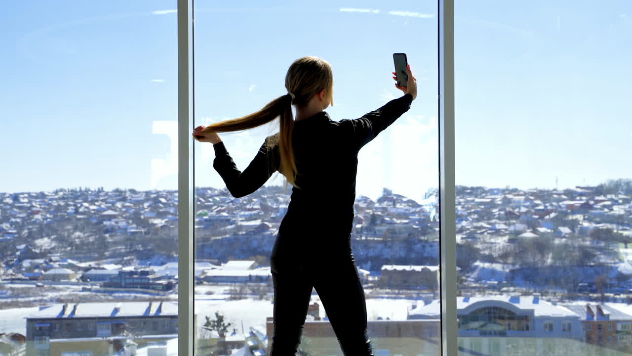 Businesswoman with mobile phone in hand. Pretty young businesswoman making selfie at workplace