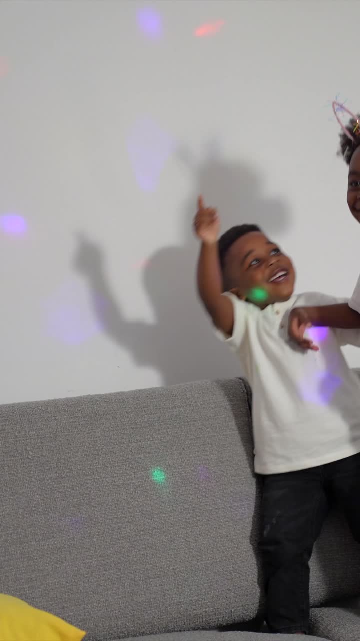 Two young boys dancing on a couch under party lights