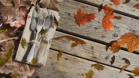 animation of leaves over cutlery and leaves on wooden background