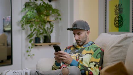 Hipster-Man-Texting-On-Mobile-Phone-While-Sitting-On-Couch-In-The-Office